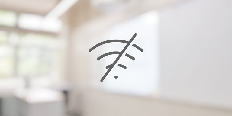 durchgestrichenes WLAN-Icon vor unscharfem Klassenraum